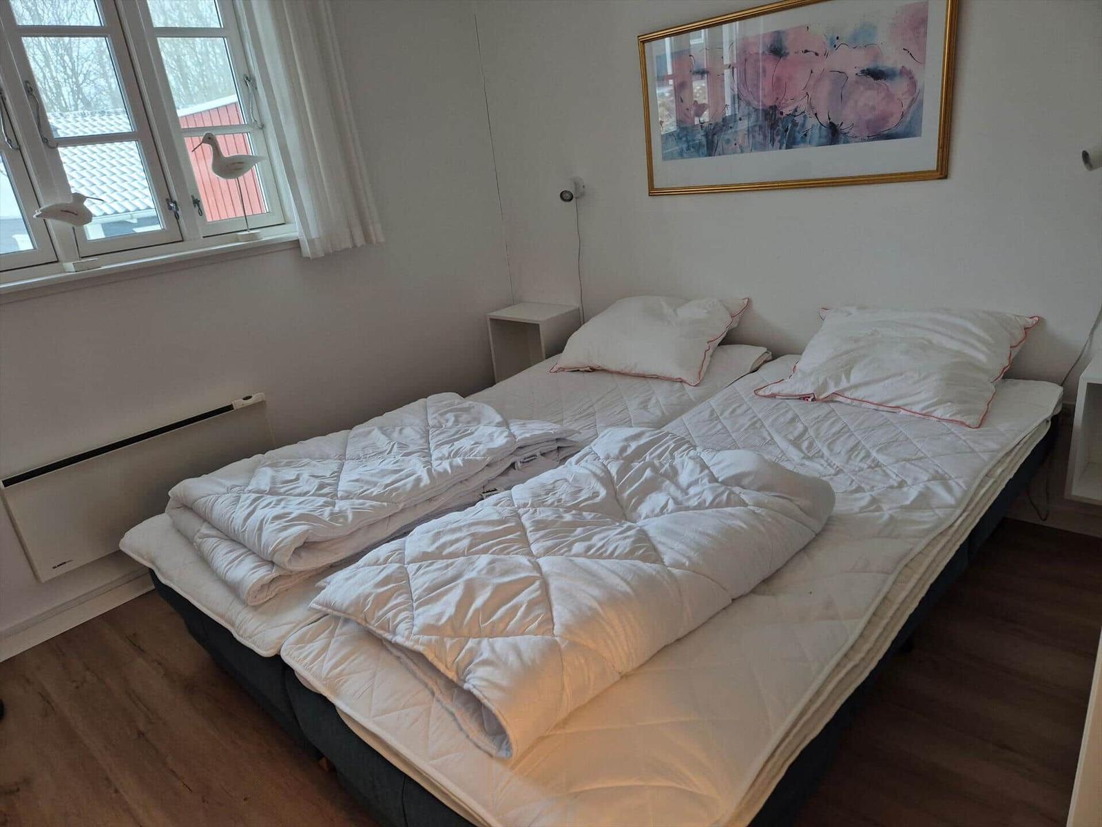 Bedroom with double bed, window, and wall art.