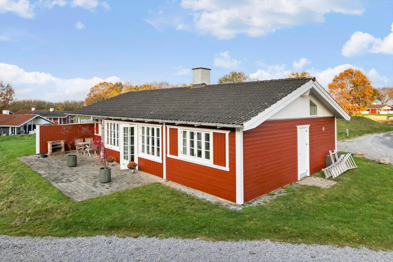 Red wooden house with terrace and grill area in autumn