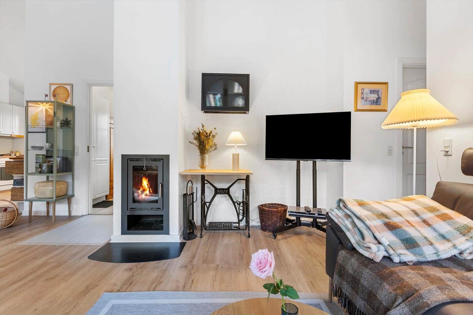 Living room with fireplace, TV, and sofa. Wooden floor and decorative items.