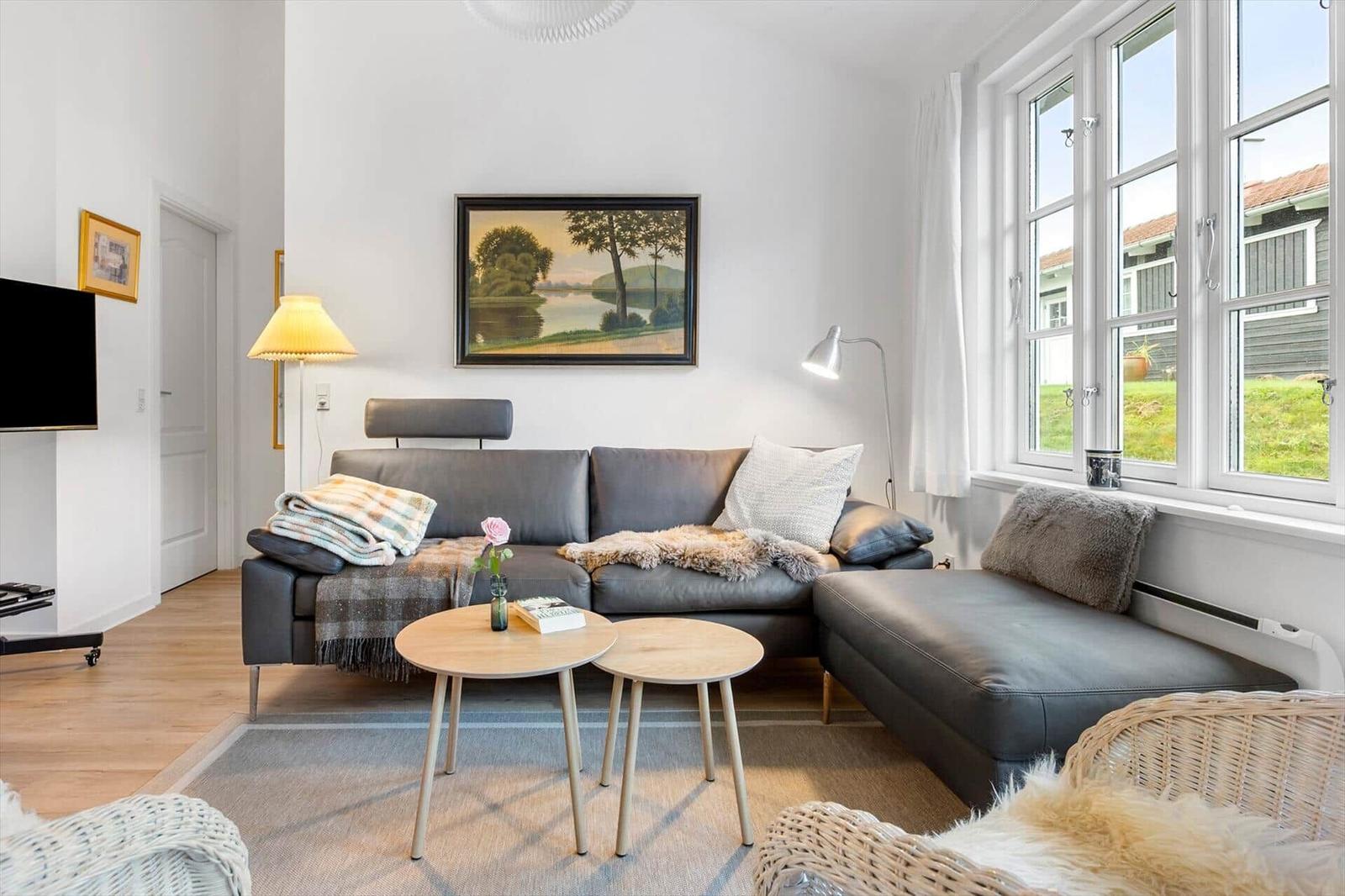 Living room with gray sofa, two round tables, and large window.