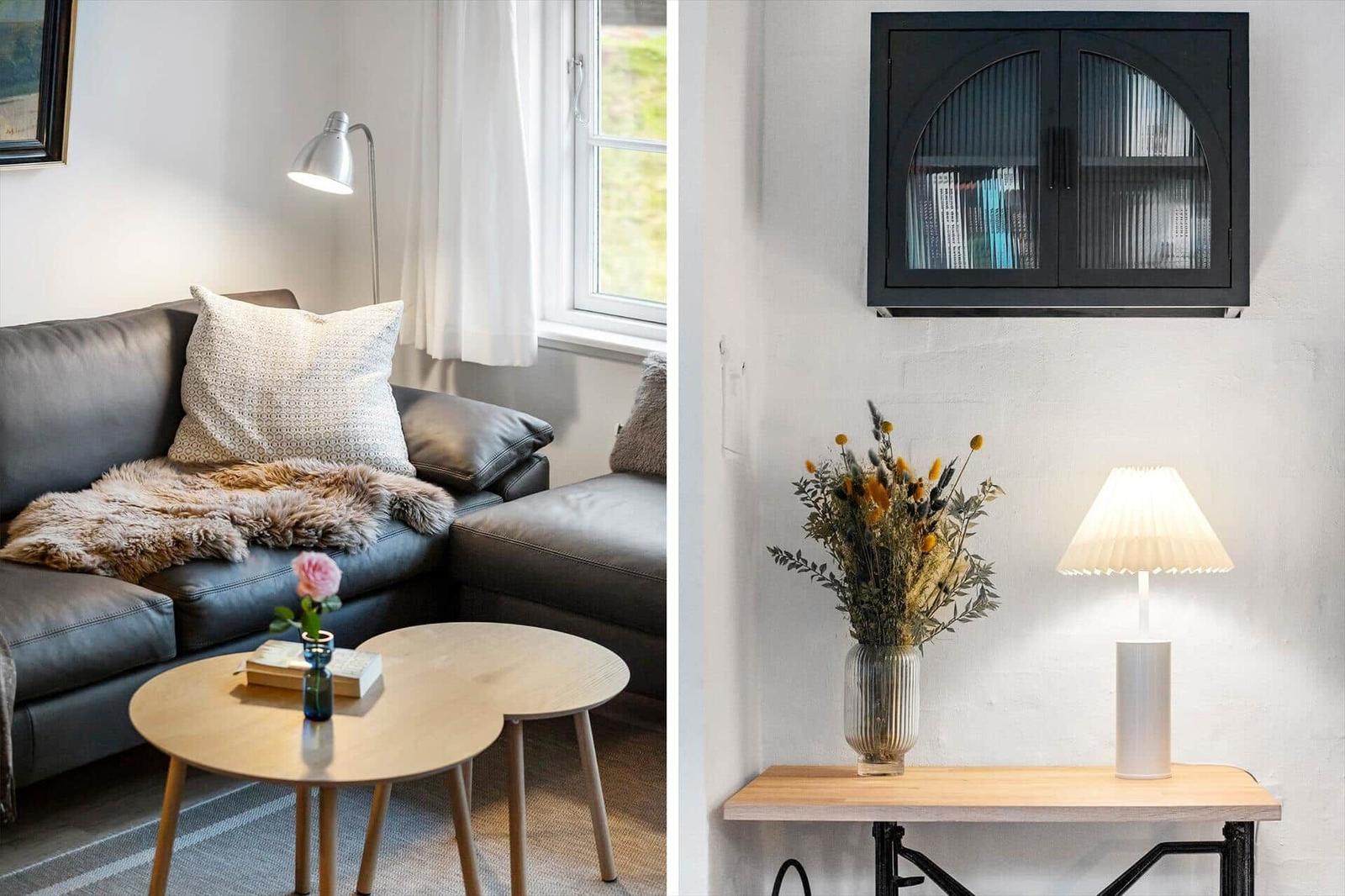 Living room with sofa, table and window. Wall cabinet with books and lamp on table.