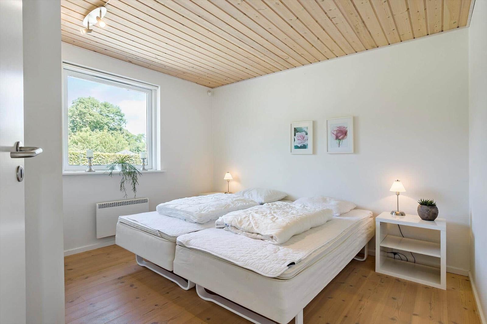 Bedroom with double bed, window, and bedside table.