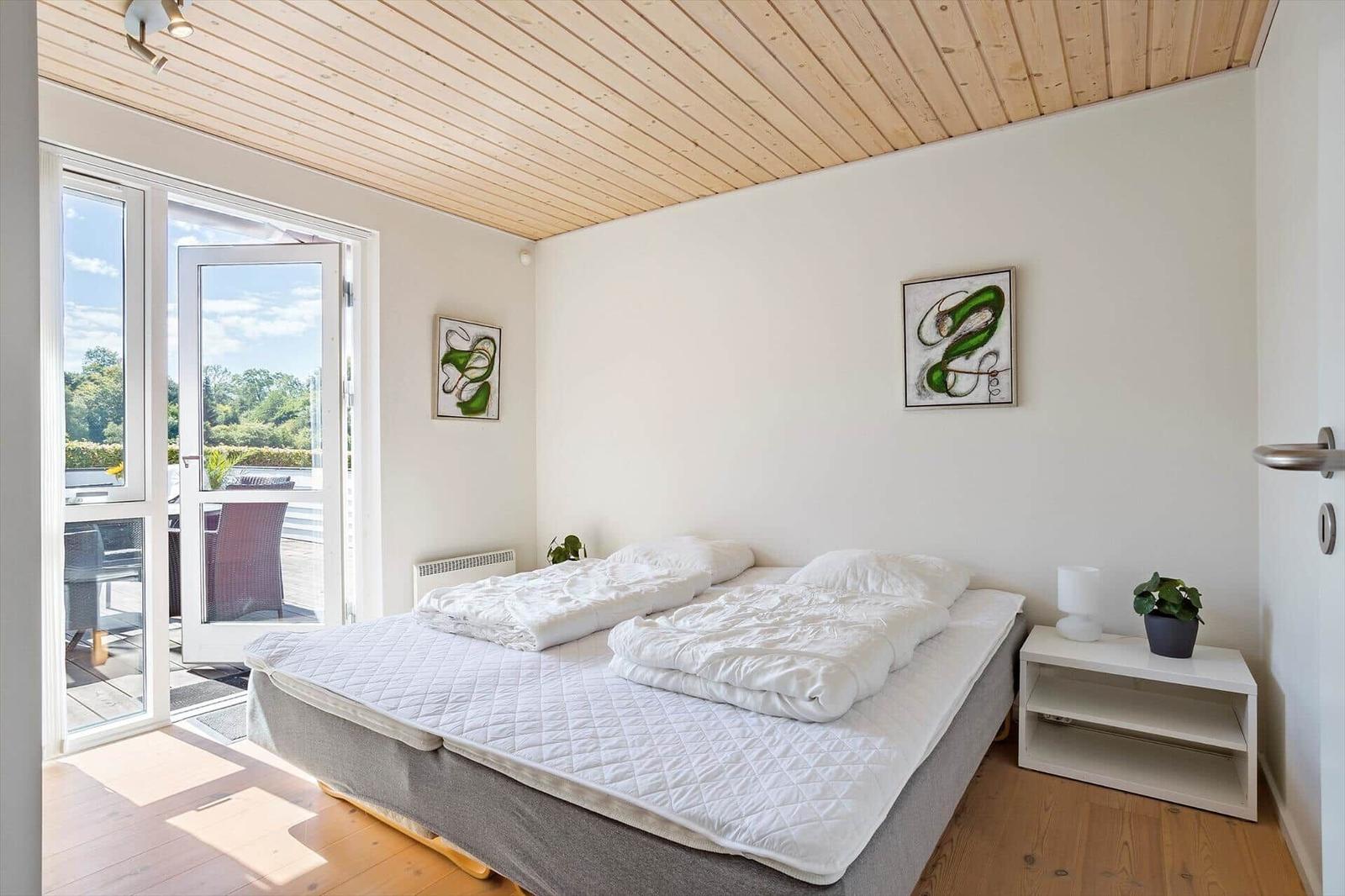 Bedroom with bed, window, and wooden ceiling.