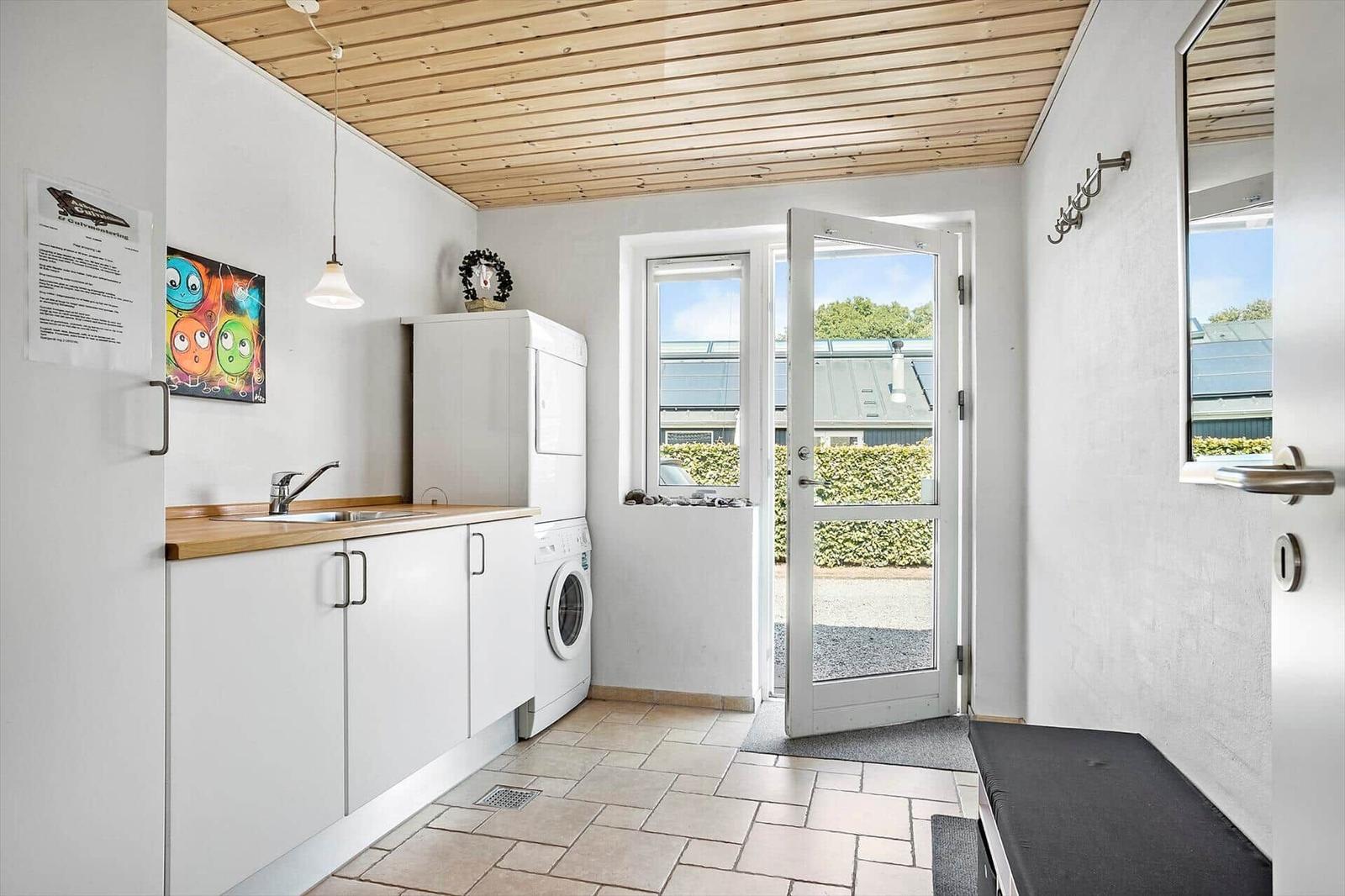 Room with washing machine, sink, and door to outdoor area.
