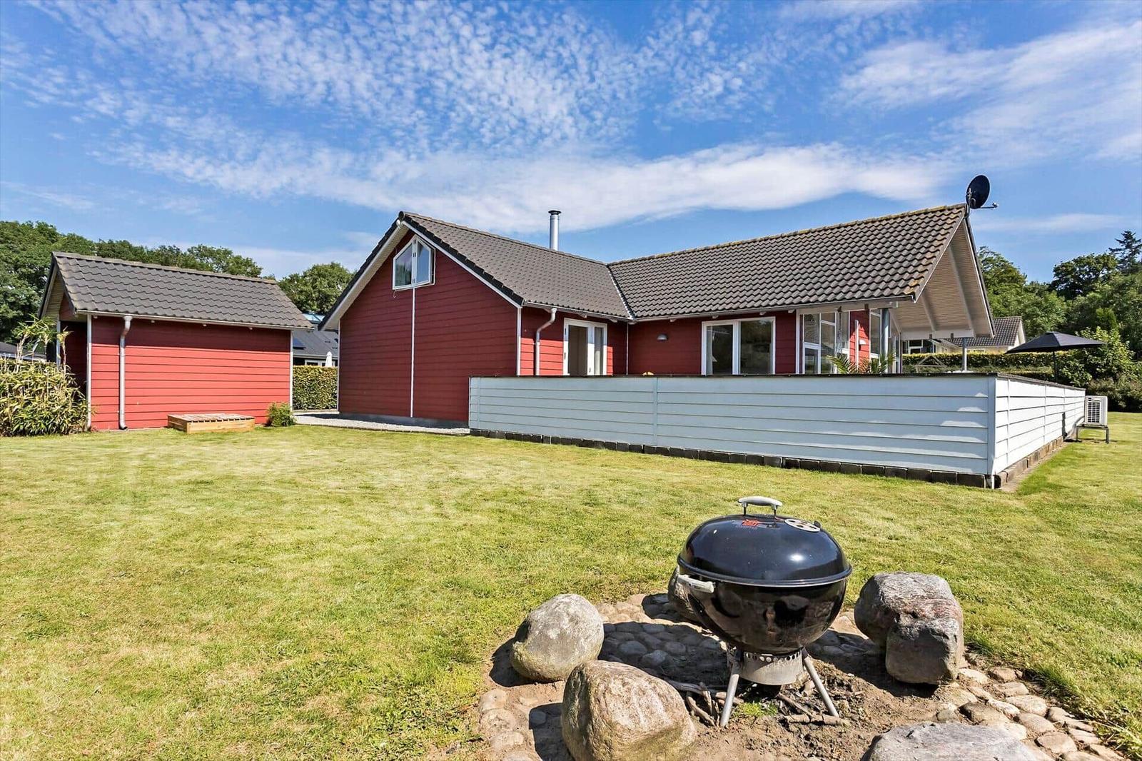 Red house with grill area and green lawn. Satellite dish and windows visible.