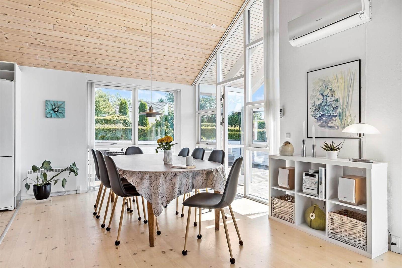 Dining room with round table, chairs, and large windows to the outdoor terrace.