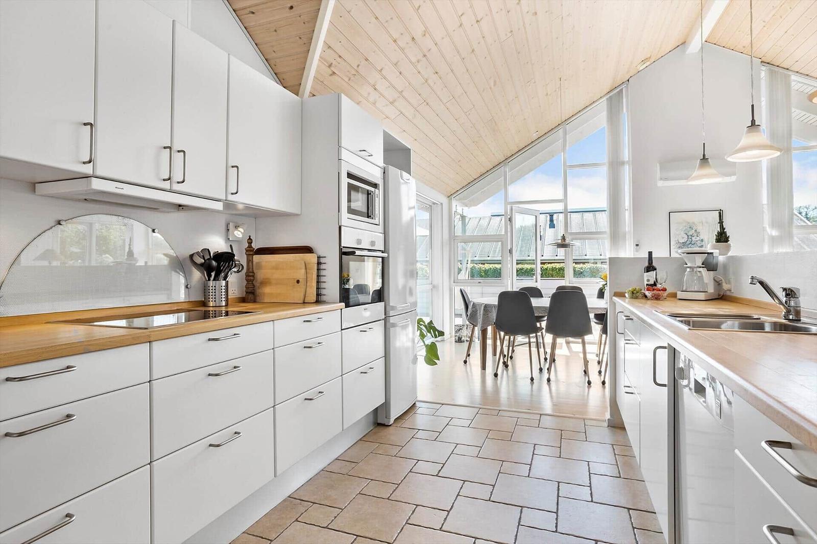 Kitchen with white cabinets, wooden countertops, and view of dining area.