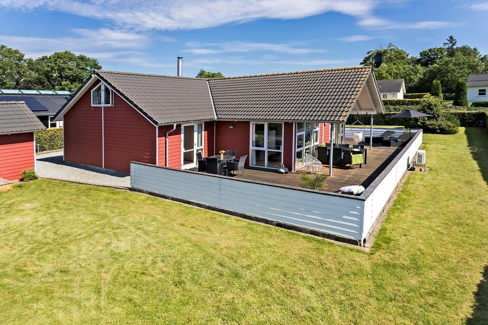 Red vacation house with terrace and garden. Outdoor area with seating.