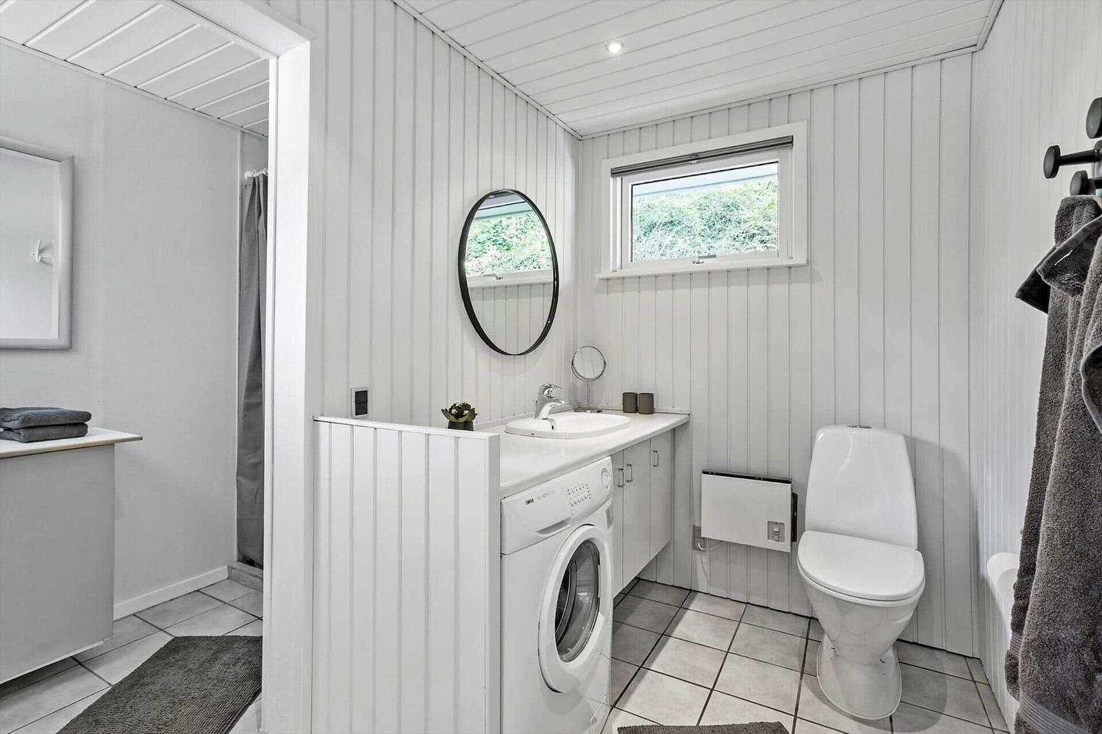 Bathroom with washing machine, toilet, and shower.