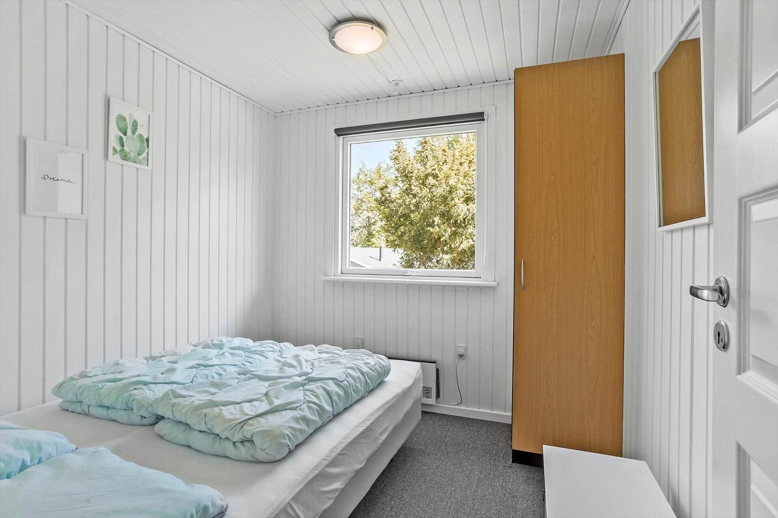 Bedroom with bed, window, and wardrobe.