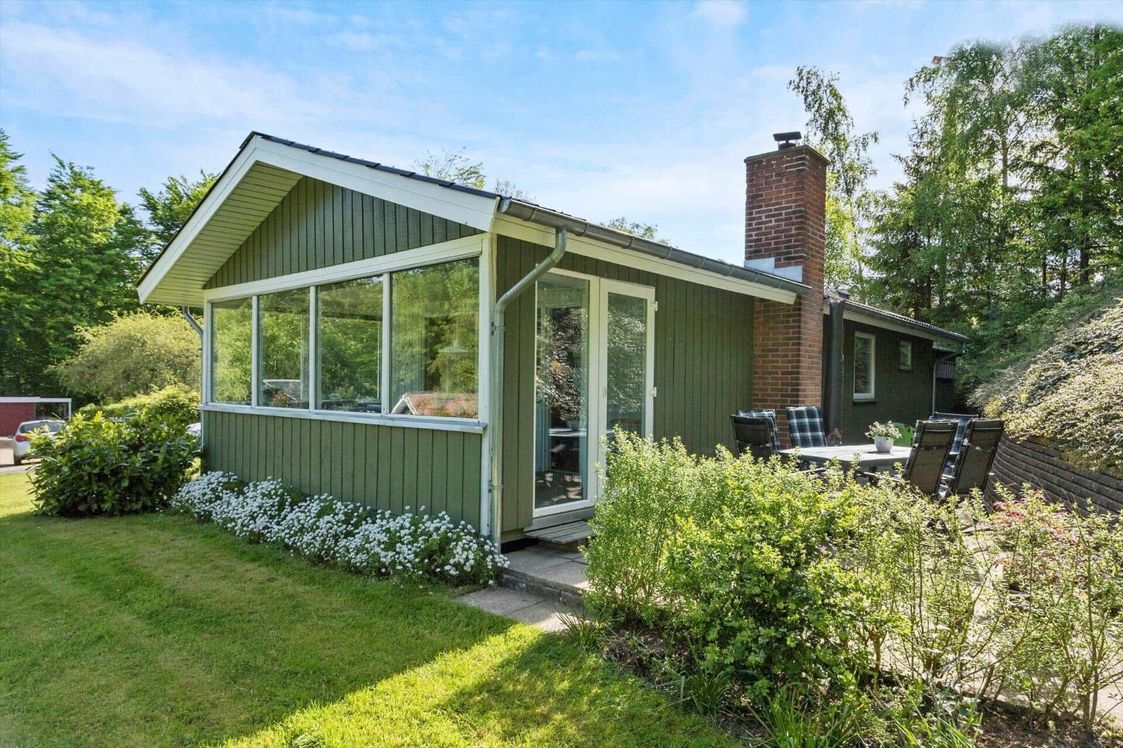 Green house with terrace and garden. Wooden siding and brick chimney.