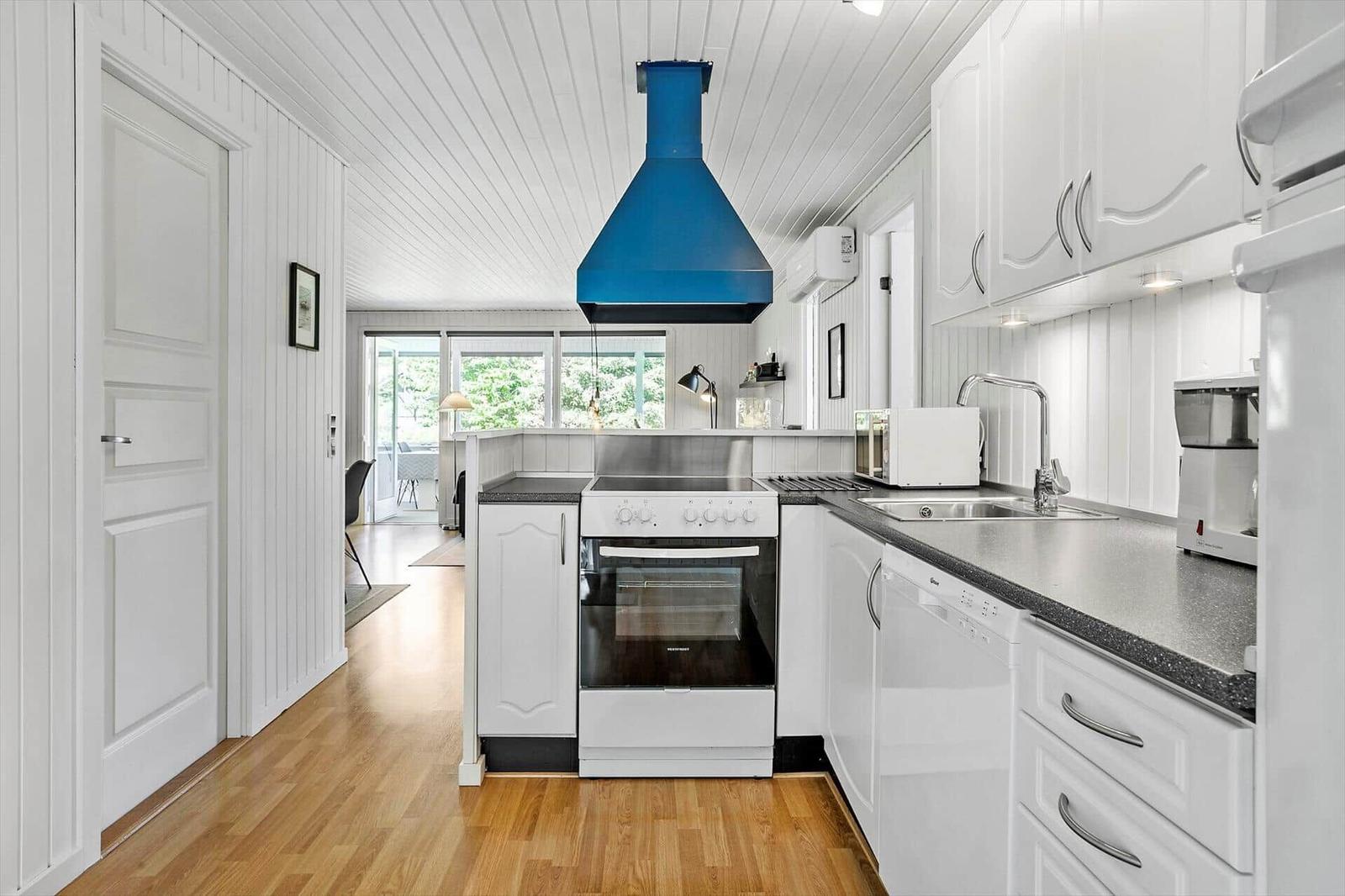 Kitchen with white cabinets, blue range hood, and hardwood floor.