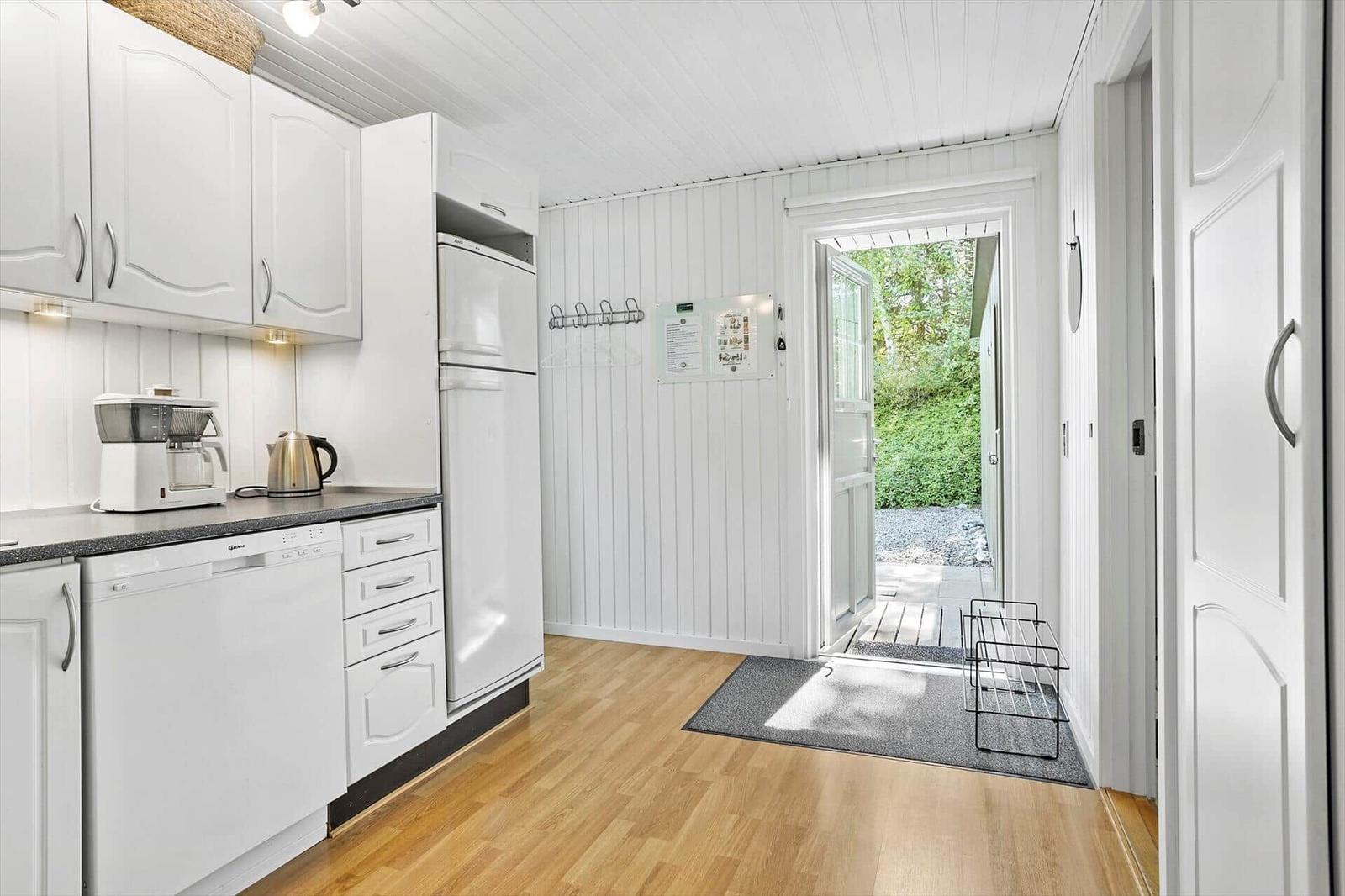 Kitchen with white cabinets, refrigerator, and doorway to terrace.