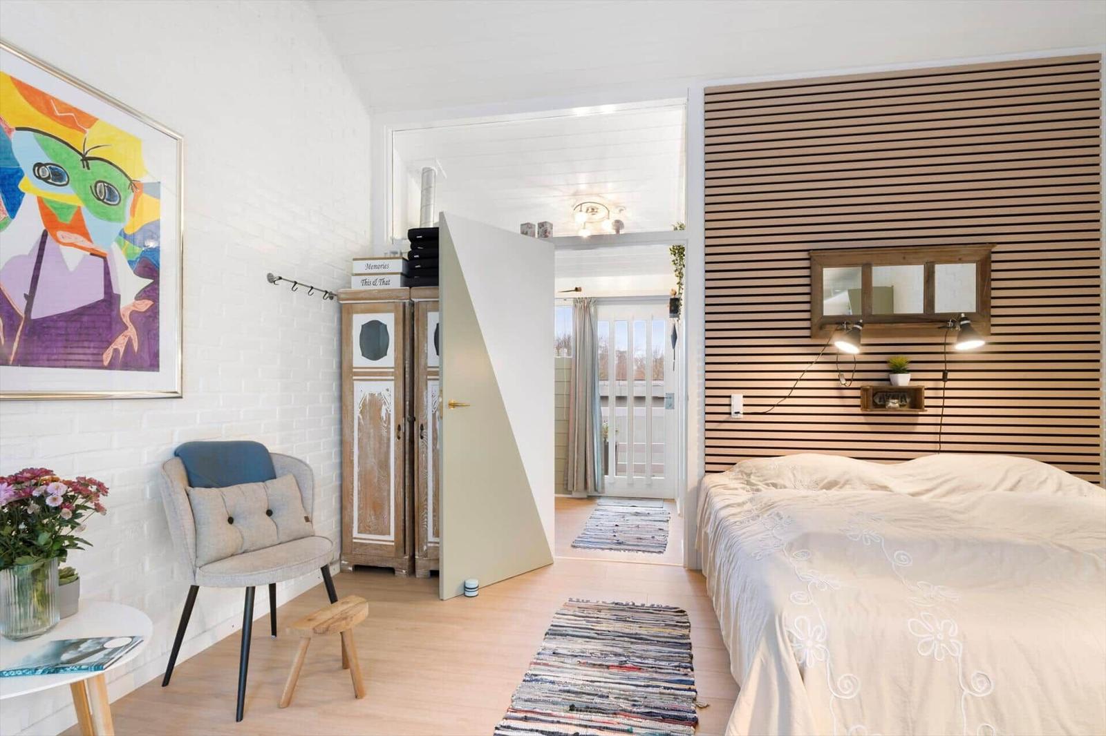 Bedroom with bed, wood panel, view to balcony