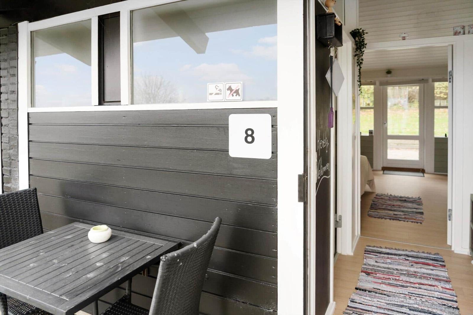 Outdoor area with table and chairs. Entrance to interior with rug.