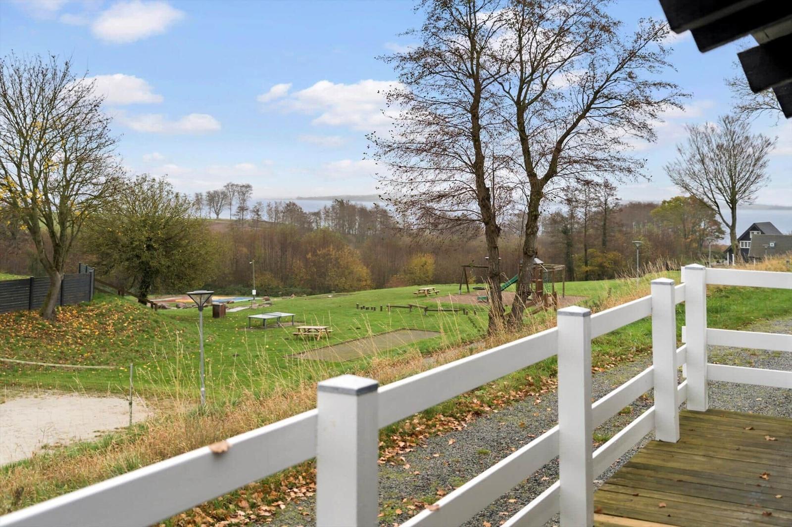 Large garden with playground and view of water and forest.