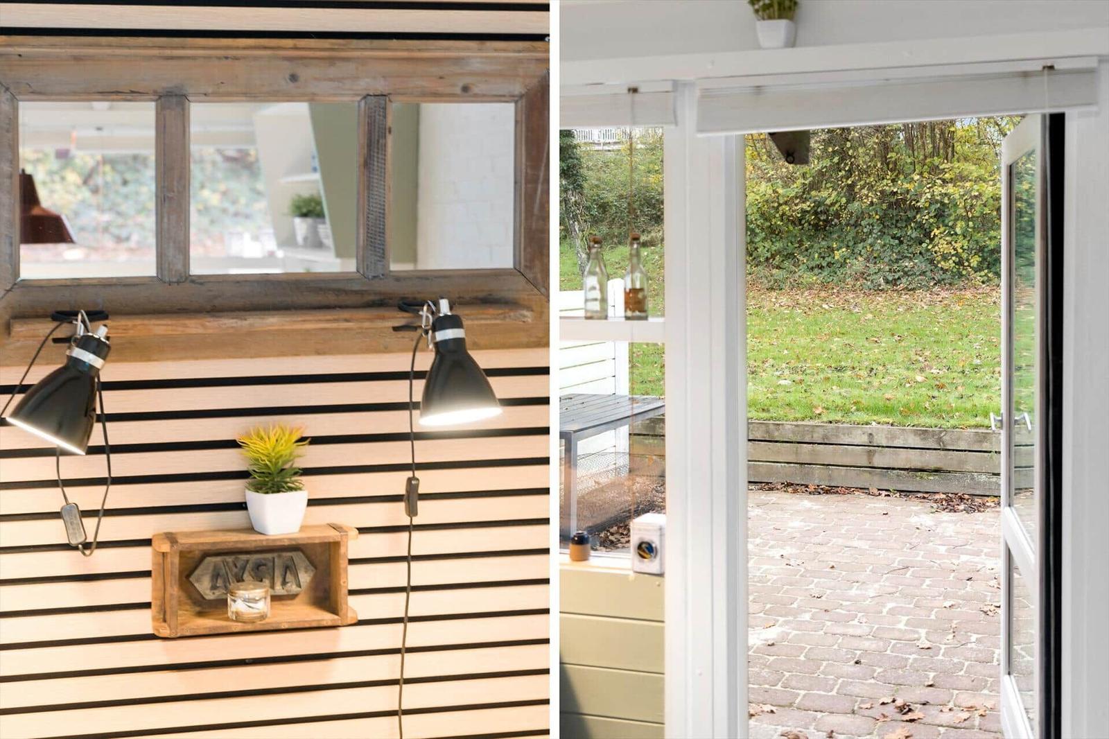 Room with wooden wall and window, view of paved courtyard with green area.