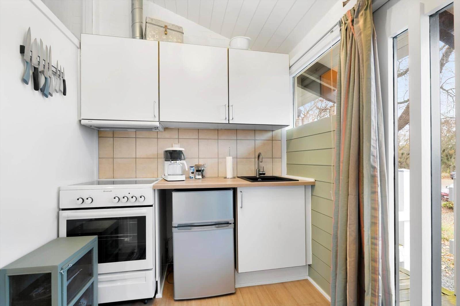 Kitchen with white cabinets, stove, refrigerator, and window.
