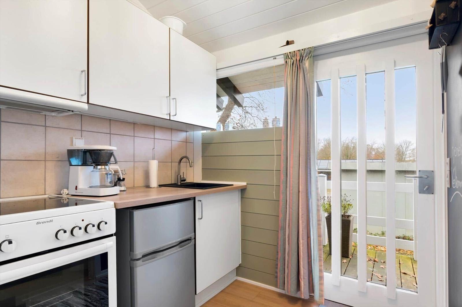 Kitchen with range hood, coffee maker, sink, and door to balcony.