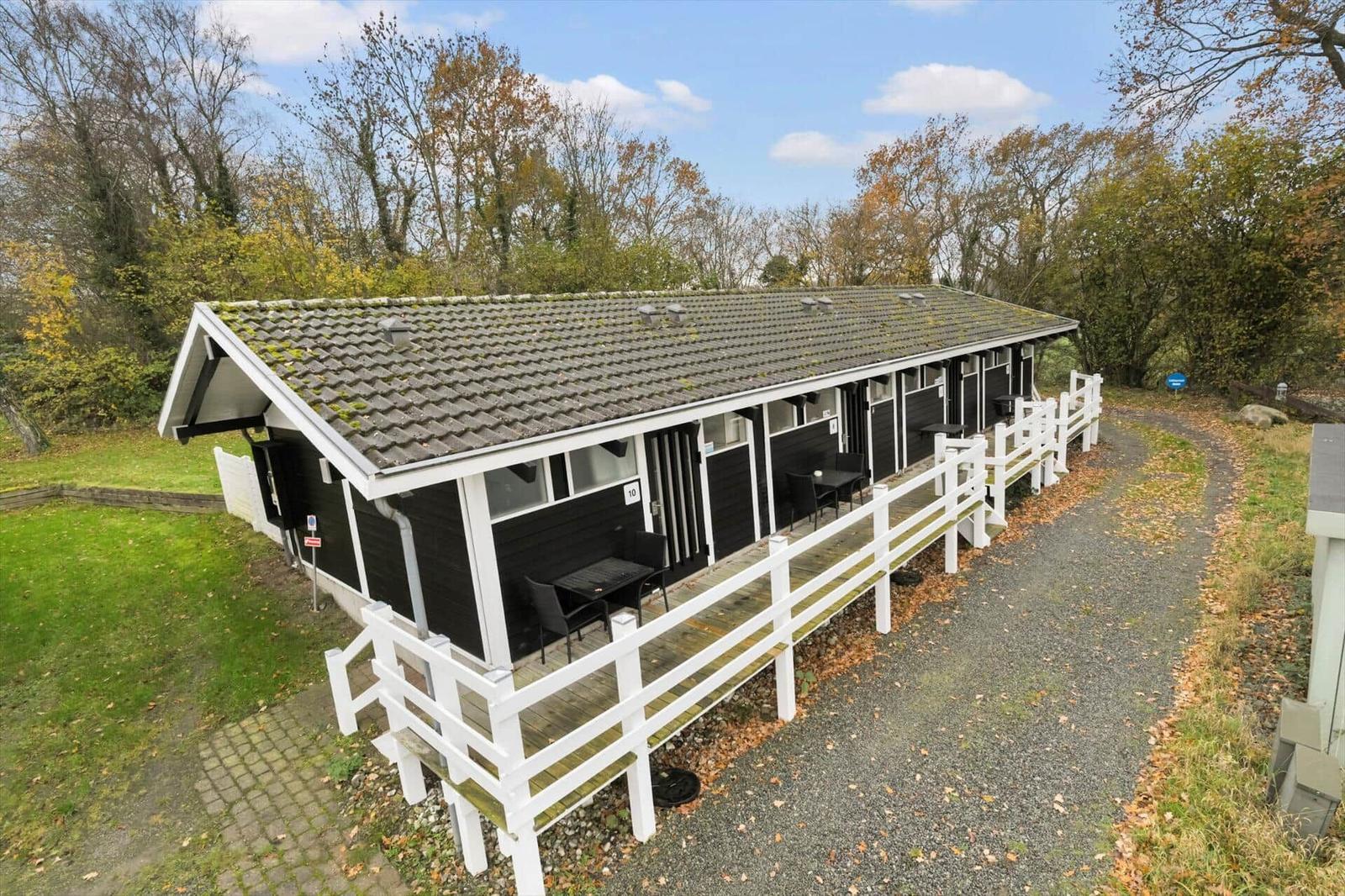 Long row of black holiday homes with white porches and tables.