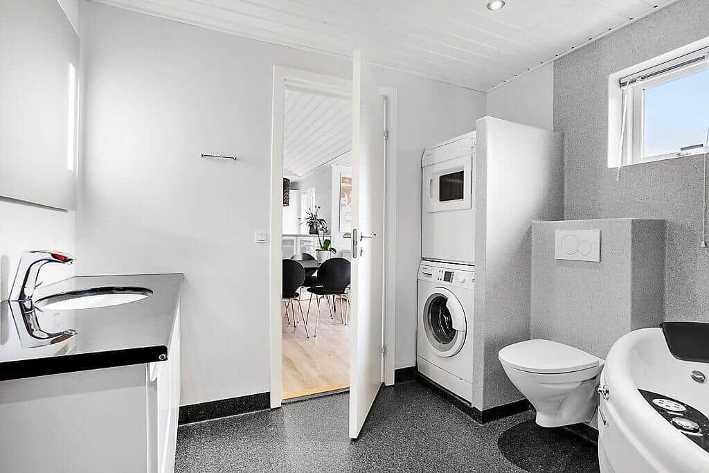 Bathroom with washing machine, toilet, and whirlpool tub.