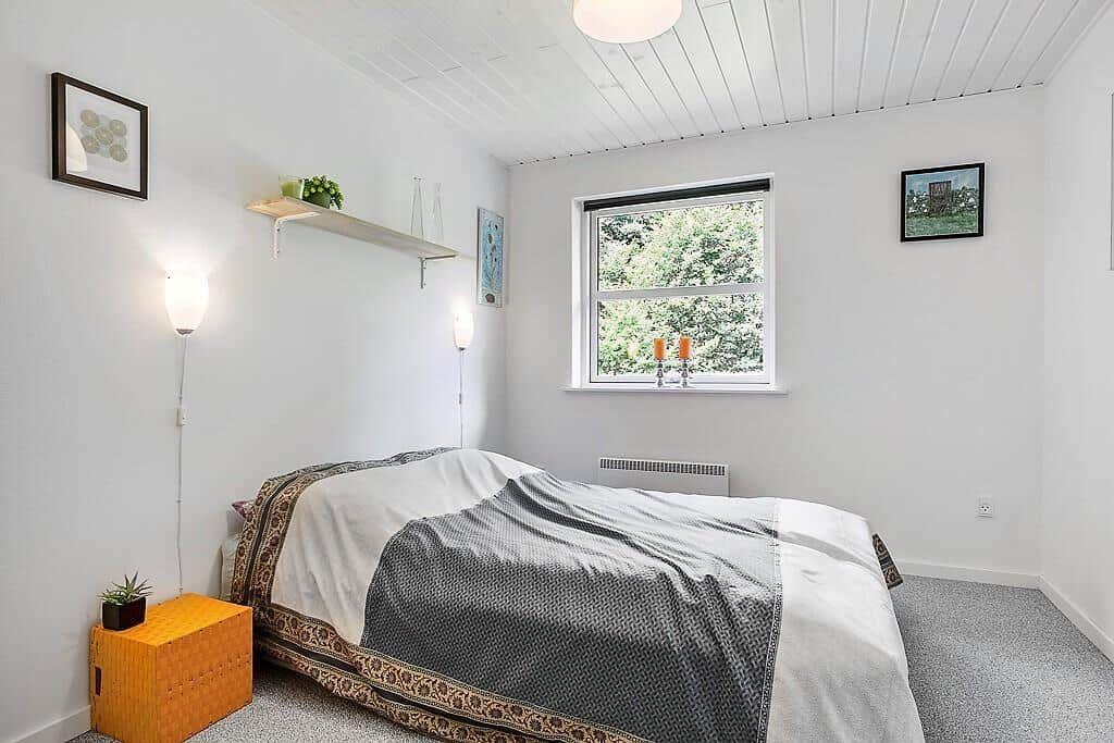 Bedroom with bed, window, and wall lamps.