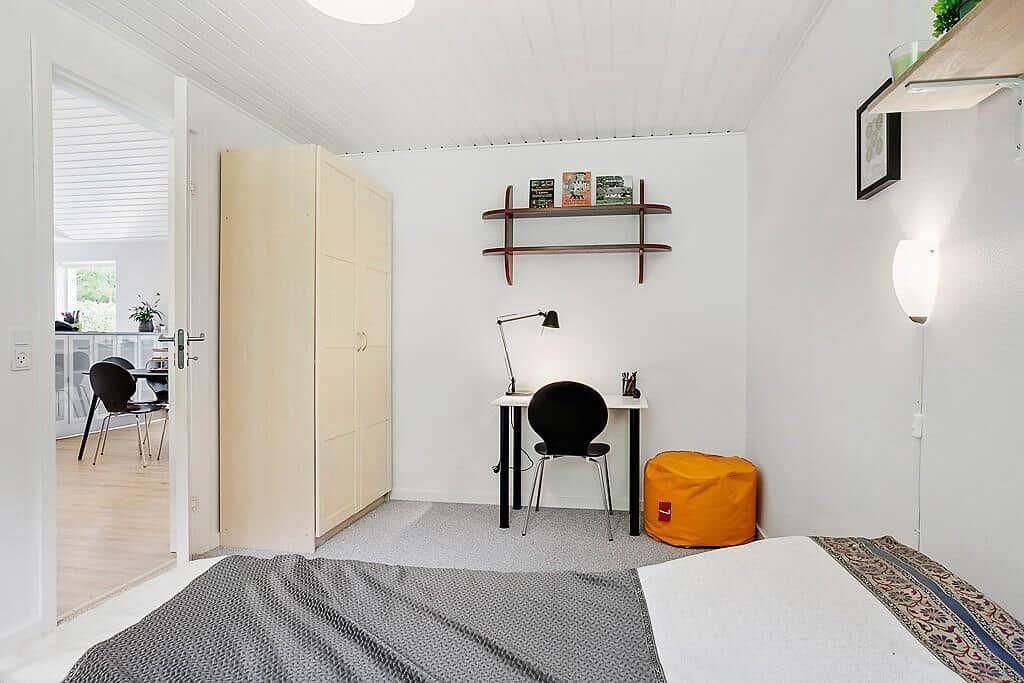 Bedroom with desk, wardrobe, and seating area.