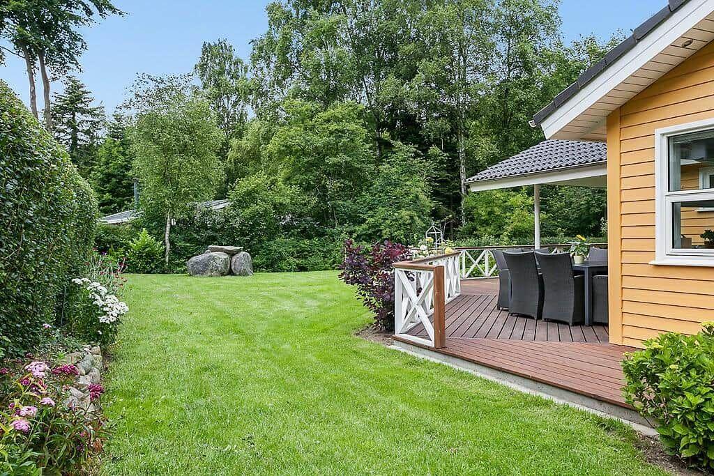 Backyard with terrace, garden, and forest in the background.