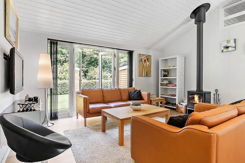 Living room with brown leather sofas, fireplace, and glass doors to terrace.