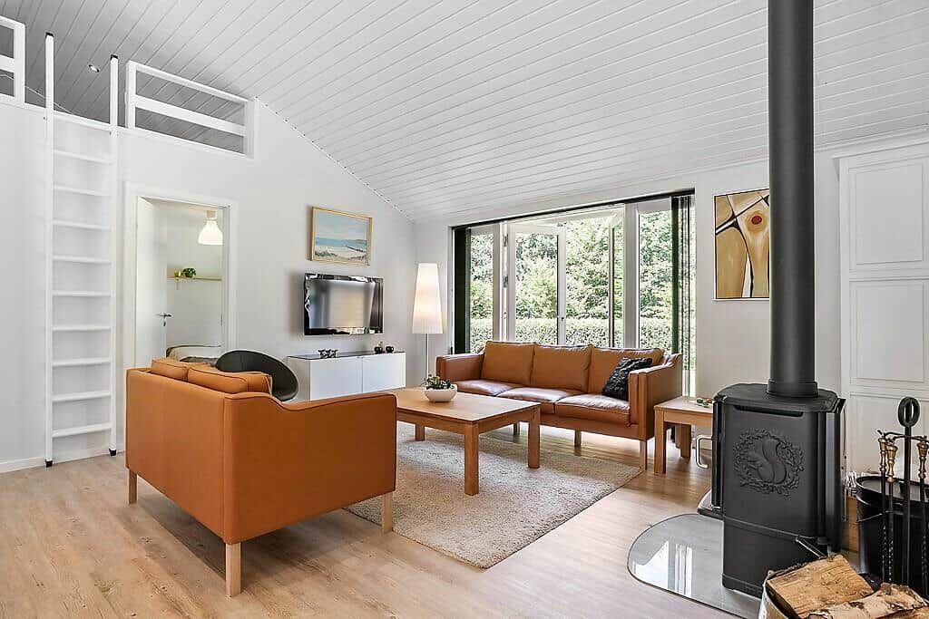 Living room with brown leather furniture, fireplace, and sleeping area above.