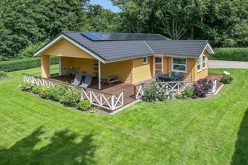 A yellow vacation home with terrace, garden, and solar panels on the roof.