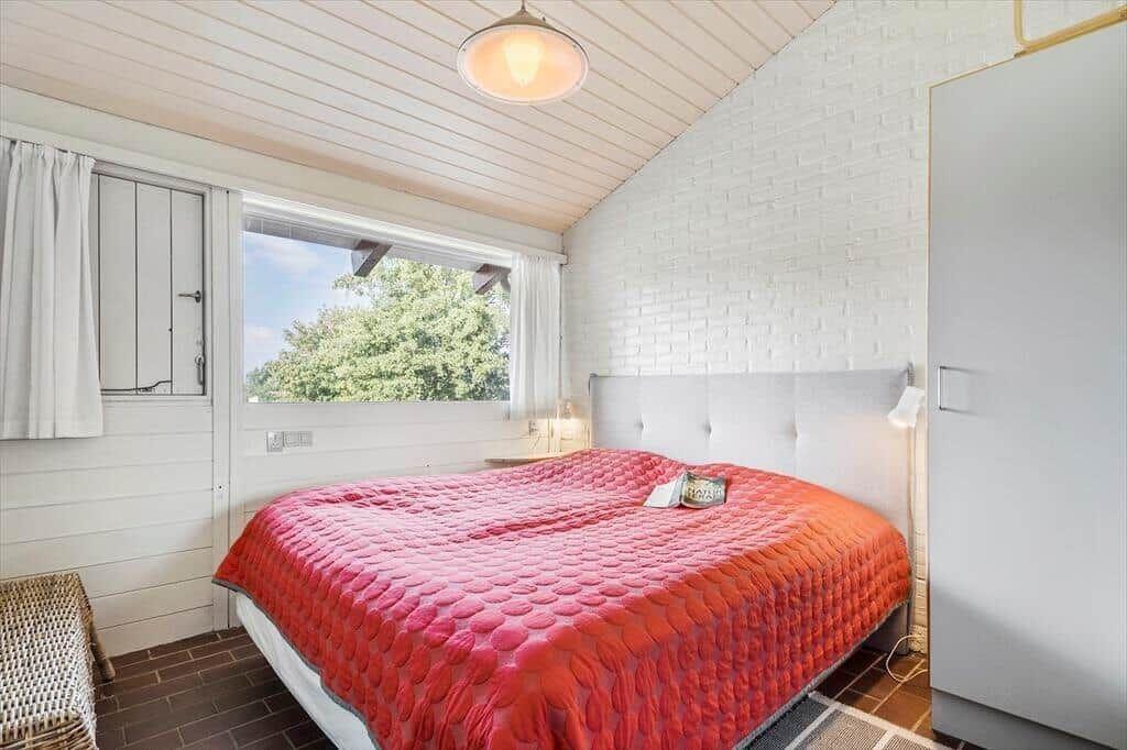 Bedroom with bed, window and white walls.