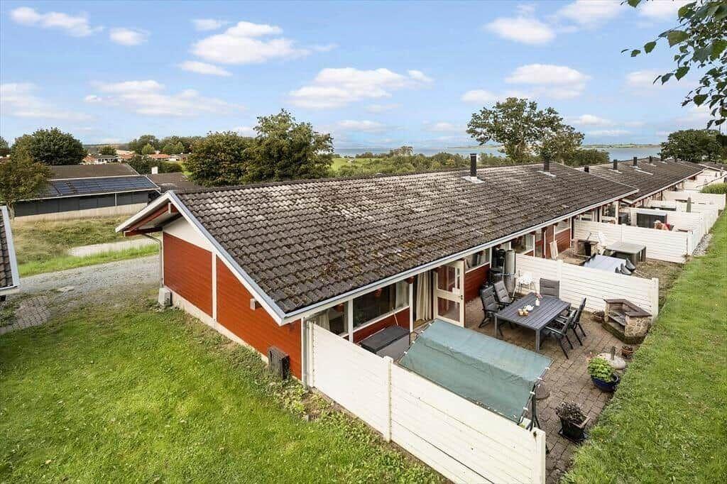 Red house with terrace and garden. View of water and green areas.