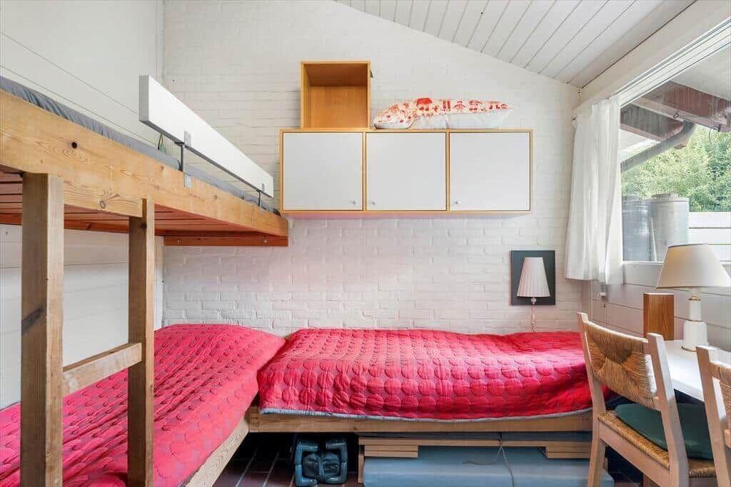 Room with double bed, daybed, and wooden shelves against white brick wall.