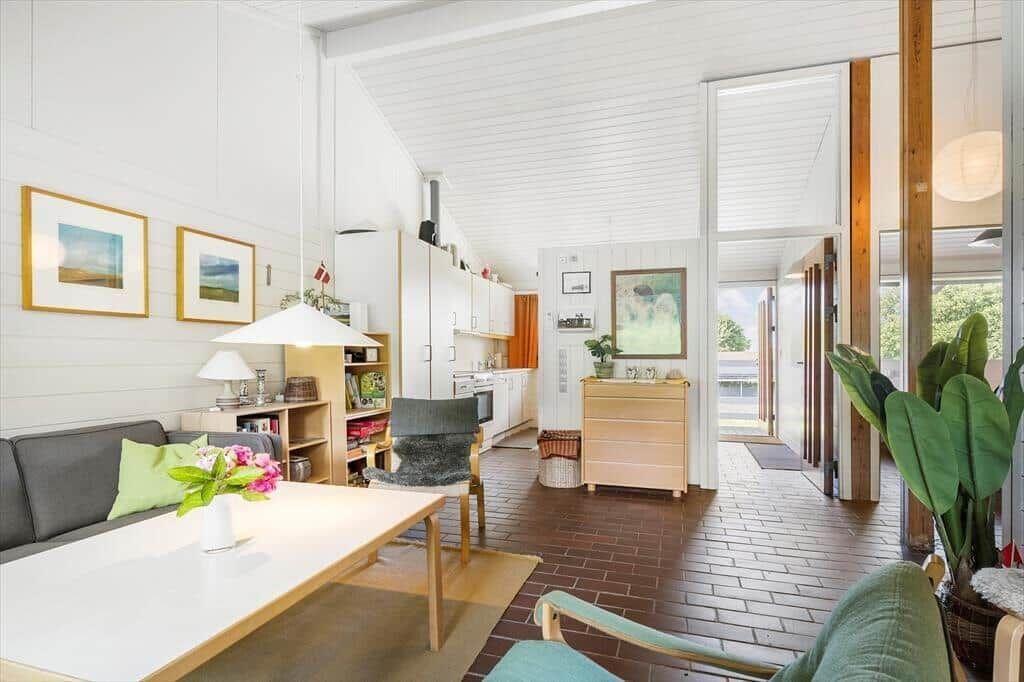 Living area with dining space and kitchen. Wooden floor and white walls.