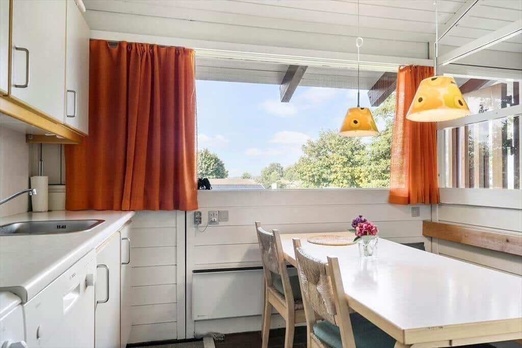 Kitchen with dining table, window, and orange curtains.