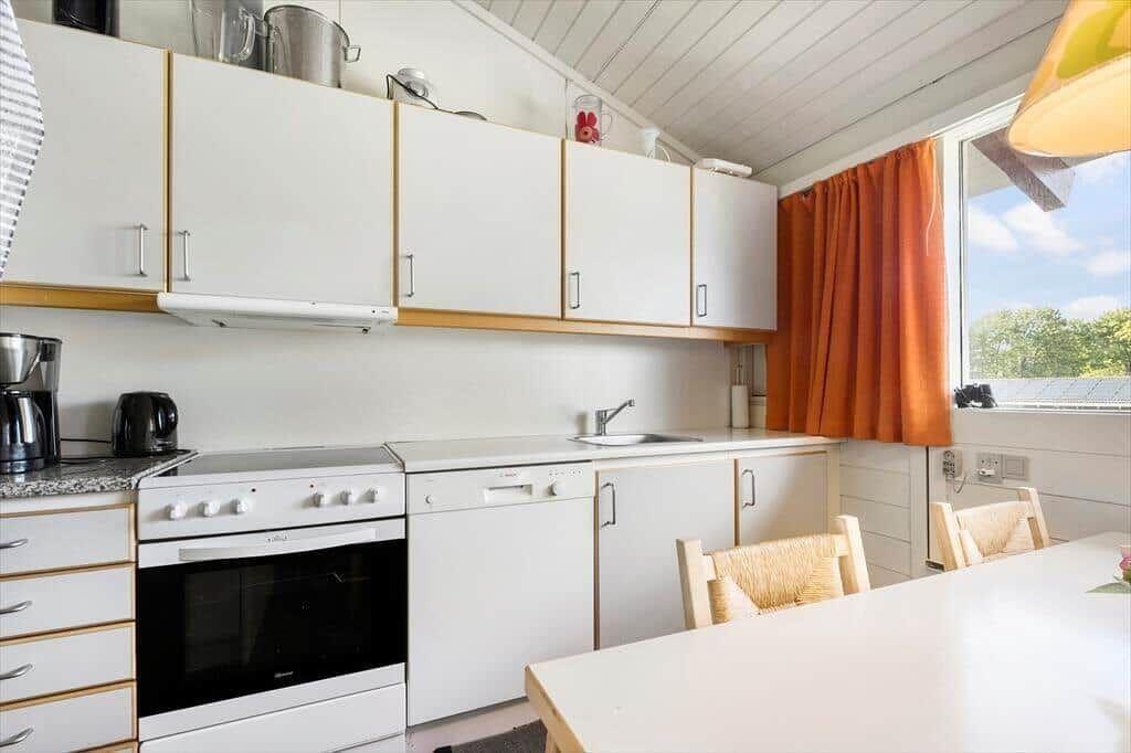 Kitchen with white cabinets, sink, and dining area with table and chairs.