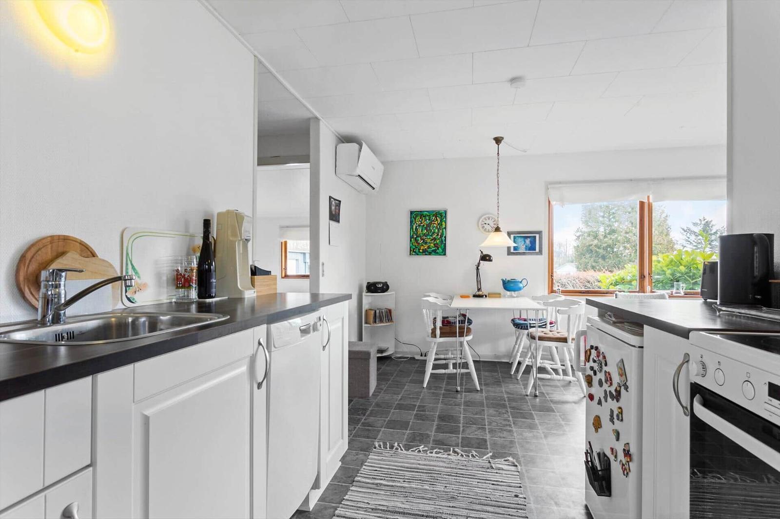 Kitchen with dining area, window, white furniture and dark countertops.