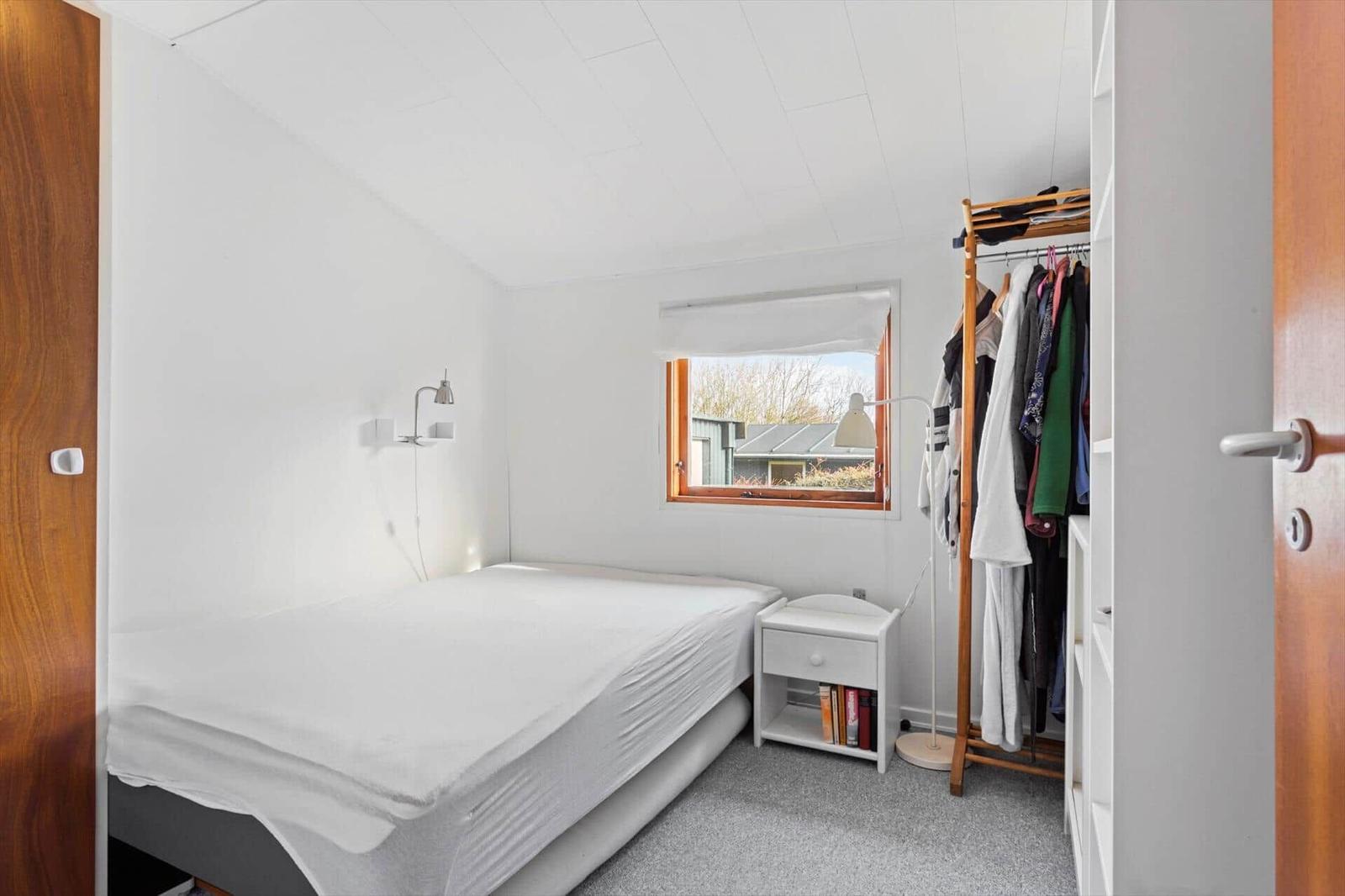 Bedroom with bed, clothes rack, and window.