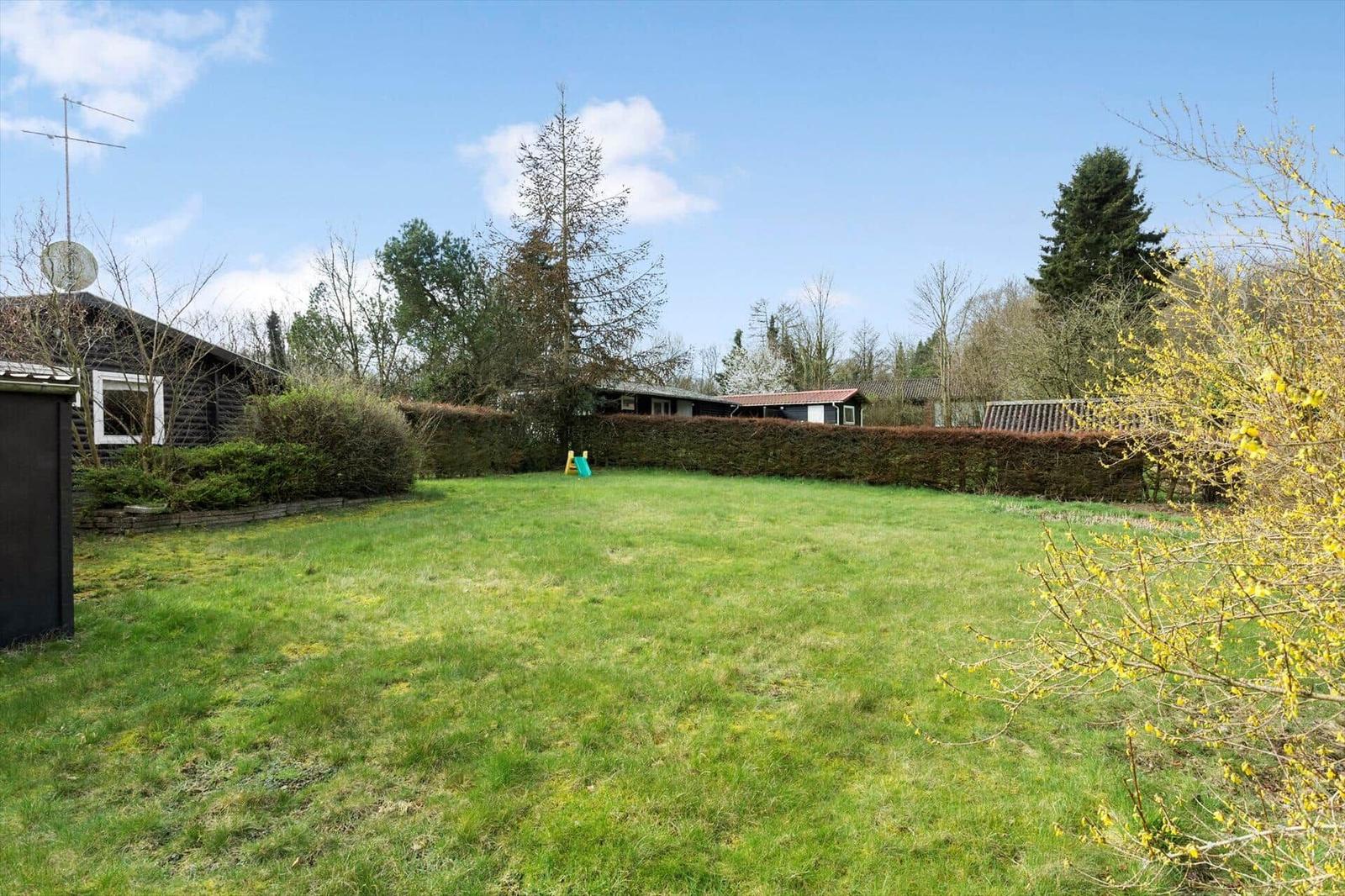Green lawn area with playground and trees in the background.
