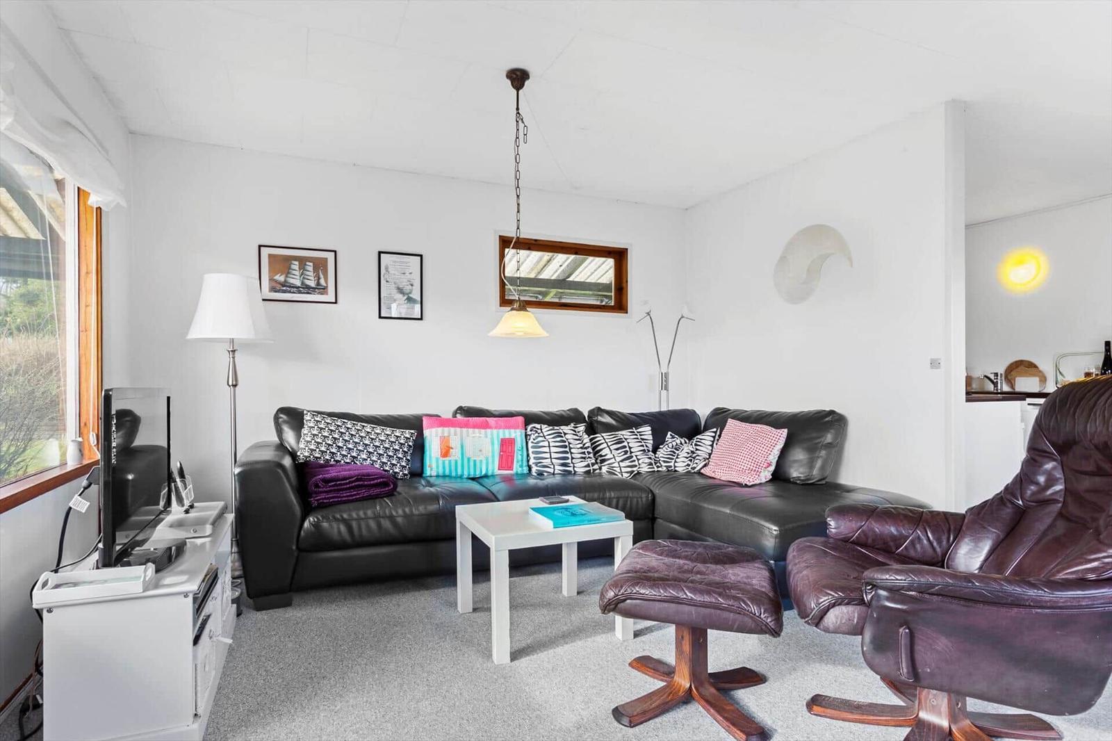 Living room with black leather sofa, wooden chair, and TV