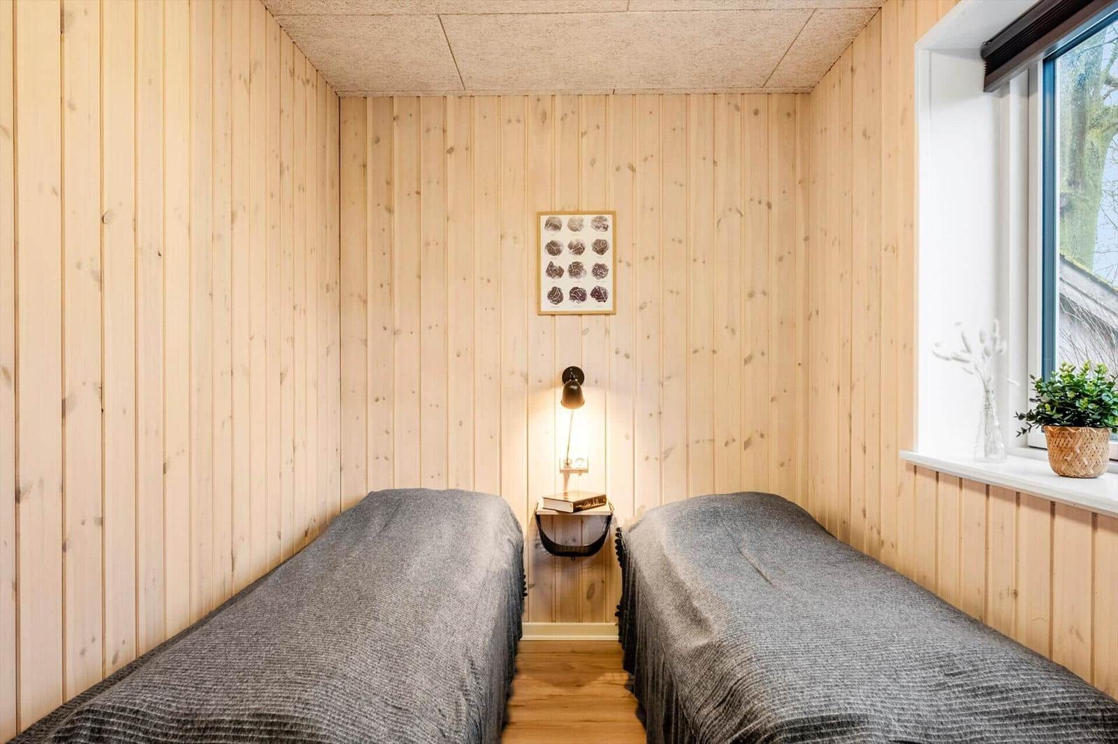 Two beds in a room with wood-paneled walls and window