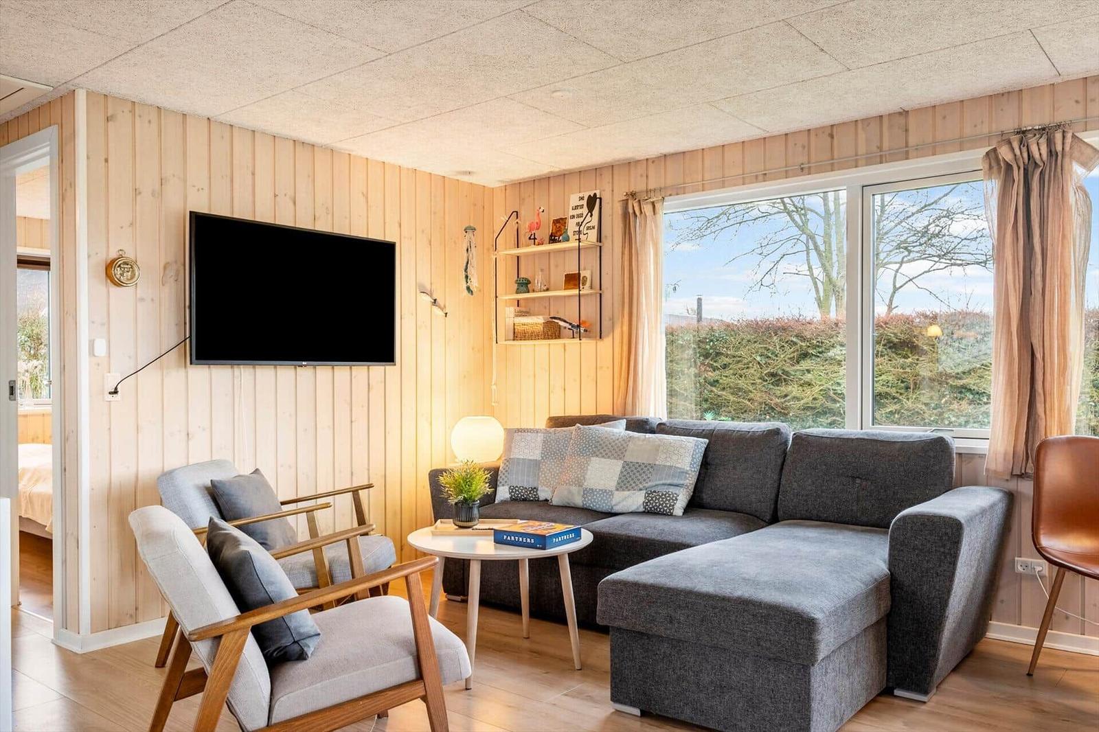 Living room with sofa, chairs, and TV mounted on wood wall