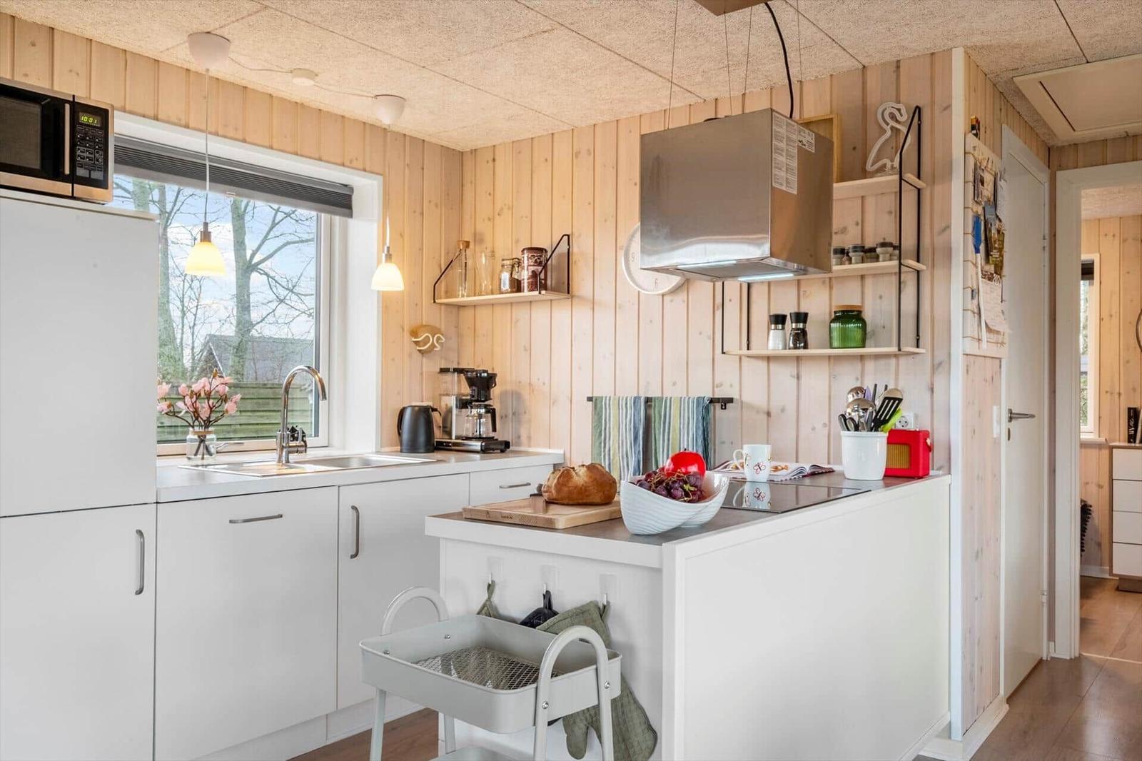 Kitchen with wooden walls, white countertop, and kitchen island.