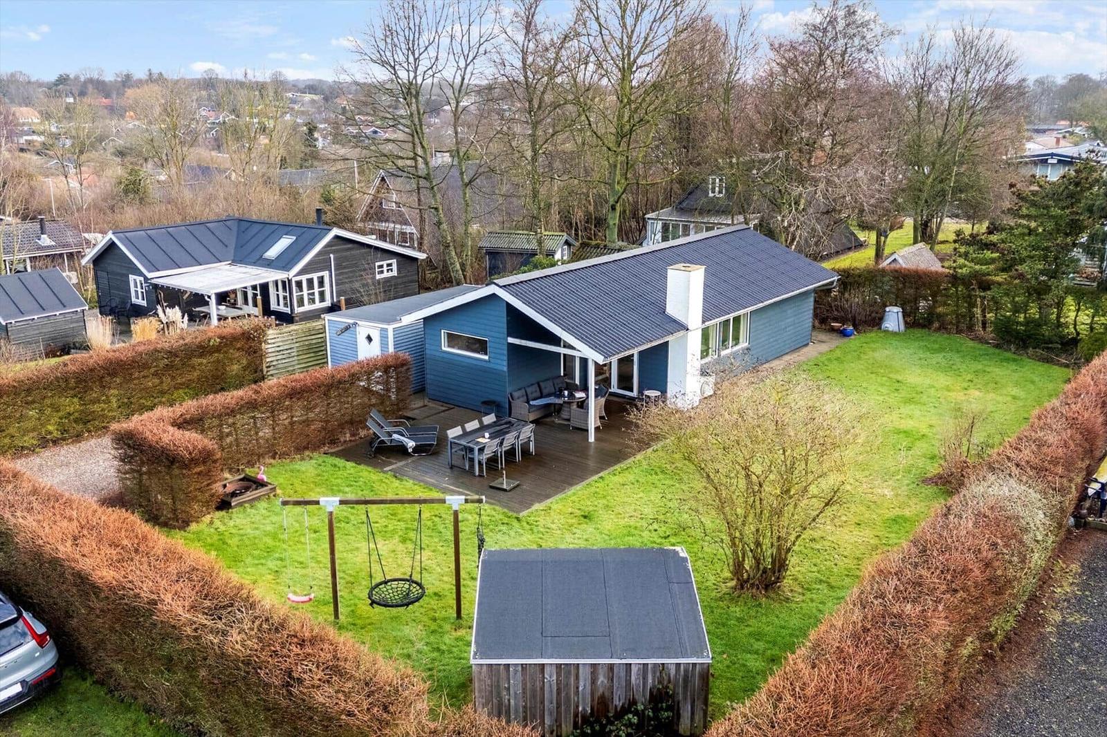 Blue house with terrace, garden, and swing set.