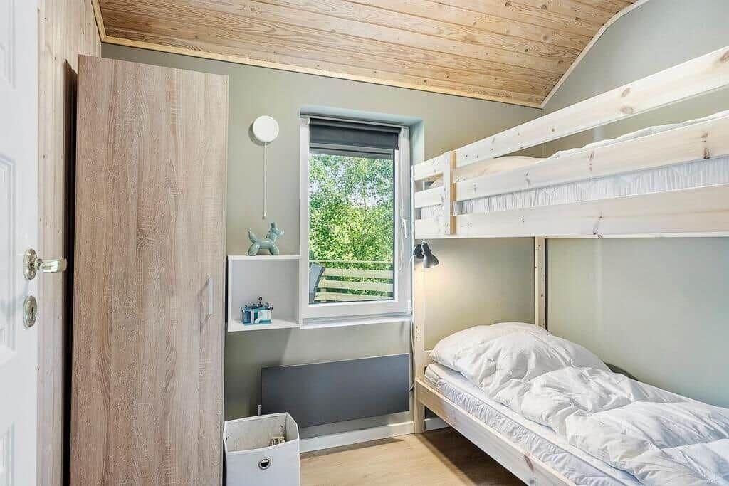 Room with bunk bed, window, and wooden floor.