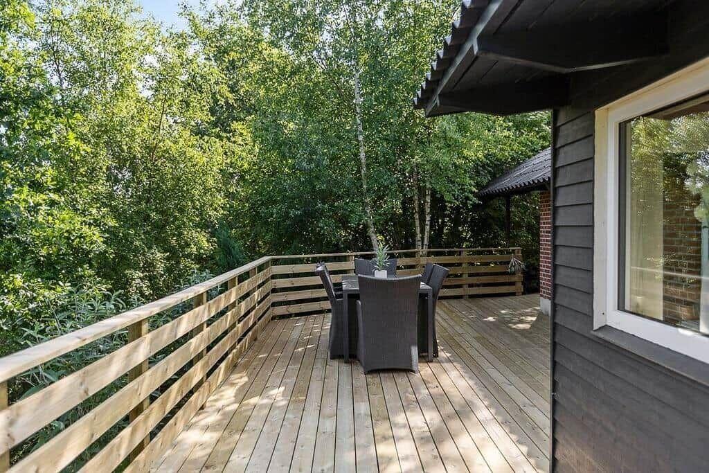 Wooden terrace with seating area and view into the forest.