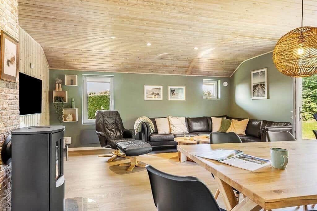 Living and dining area with wooden ceiling, sofa, dining table, and fireplace.