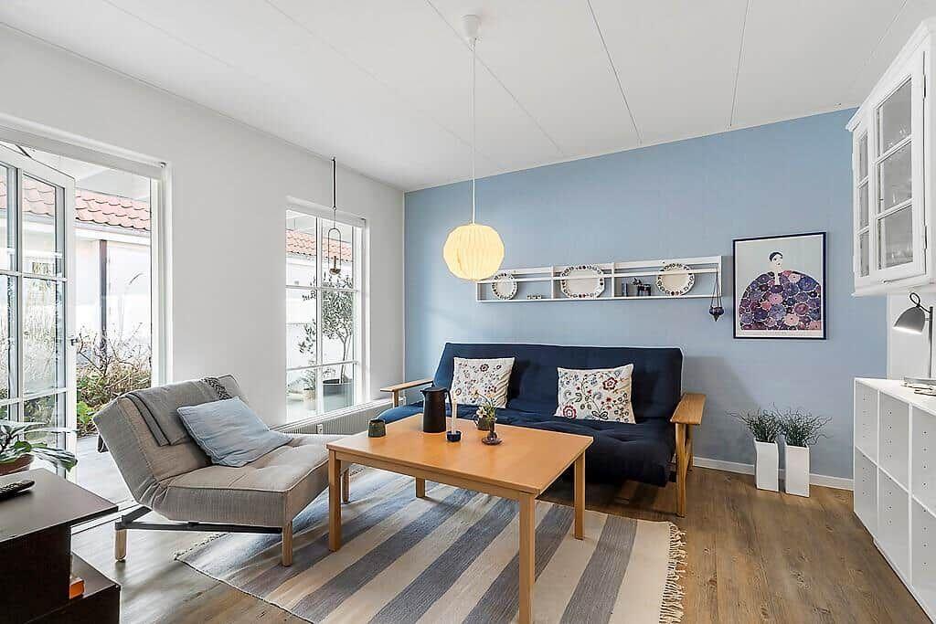 Living room with blue wall, sofa, coffee table, and windows to terrace.