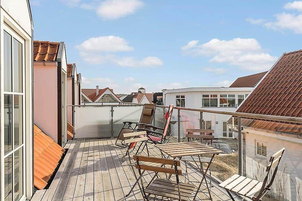 Terrace with table, chairs, and view of rooftops.